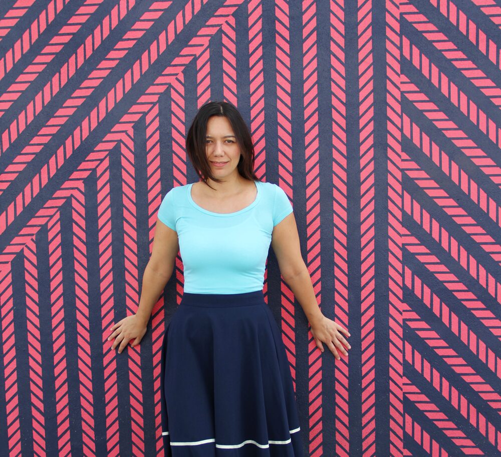 Coco wearing an aqua jersey top with a navy midi skirt.