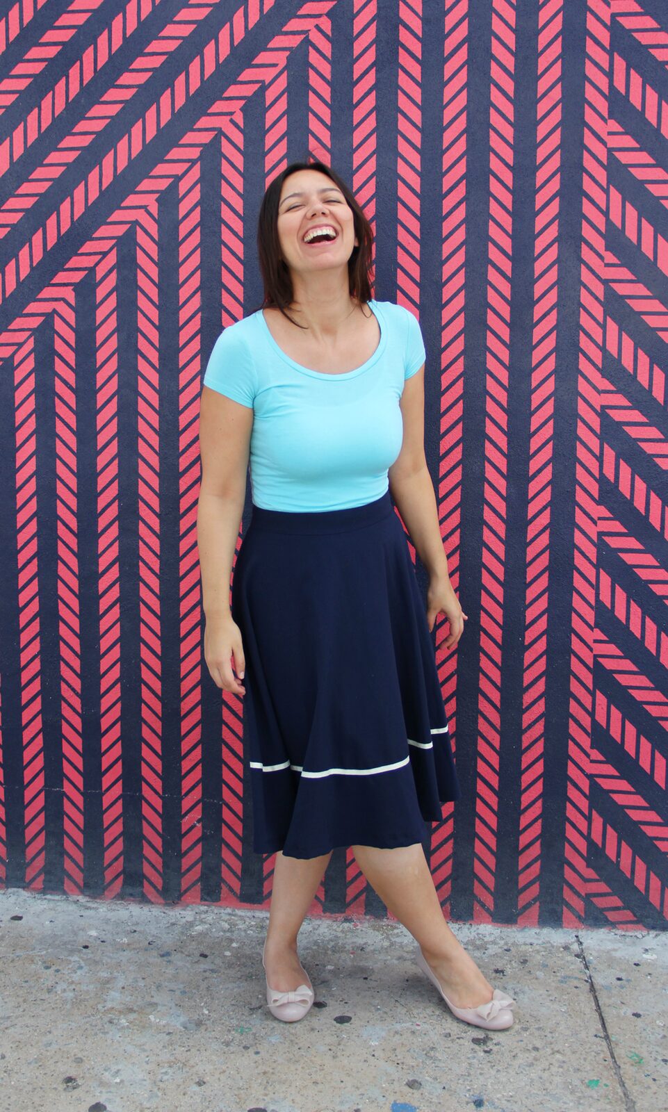 Coco wearing an aqua jersey top with a navy midi skirt.