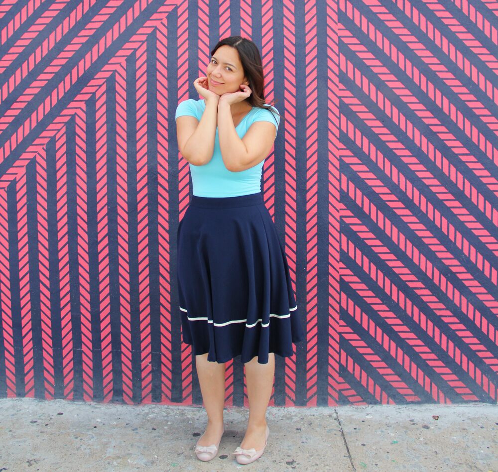 Coco wearing an aqua jersey top with a navy midi skirt.