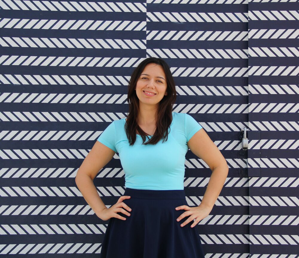Coco wearing an aqua jersey top with a navy midi skirt.