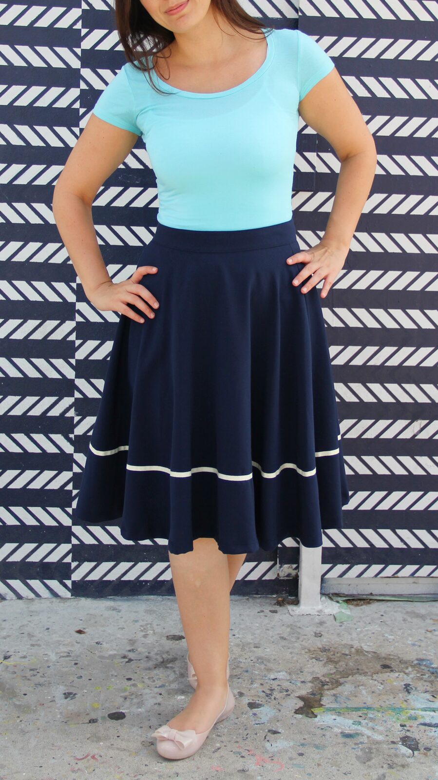 Coco wearing an aqua jersey top with a navy midi skirt.