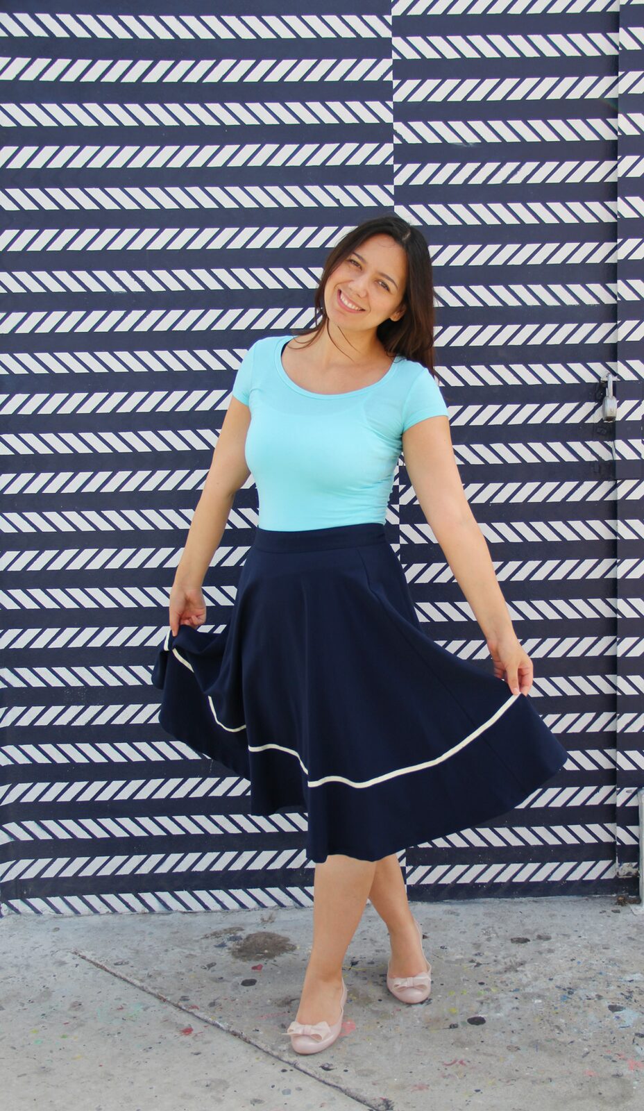 Coco wearing an aqua jersey top with a navy midi skirt.