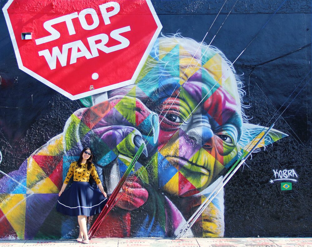 Yoda Stop Wars Mural in Wynwood Miami. Horse all over pattern sweater in mustard with navy midi skirt and nude flats