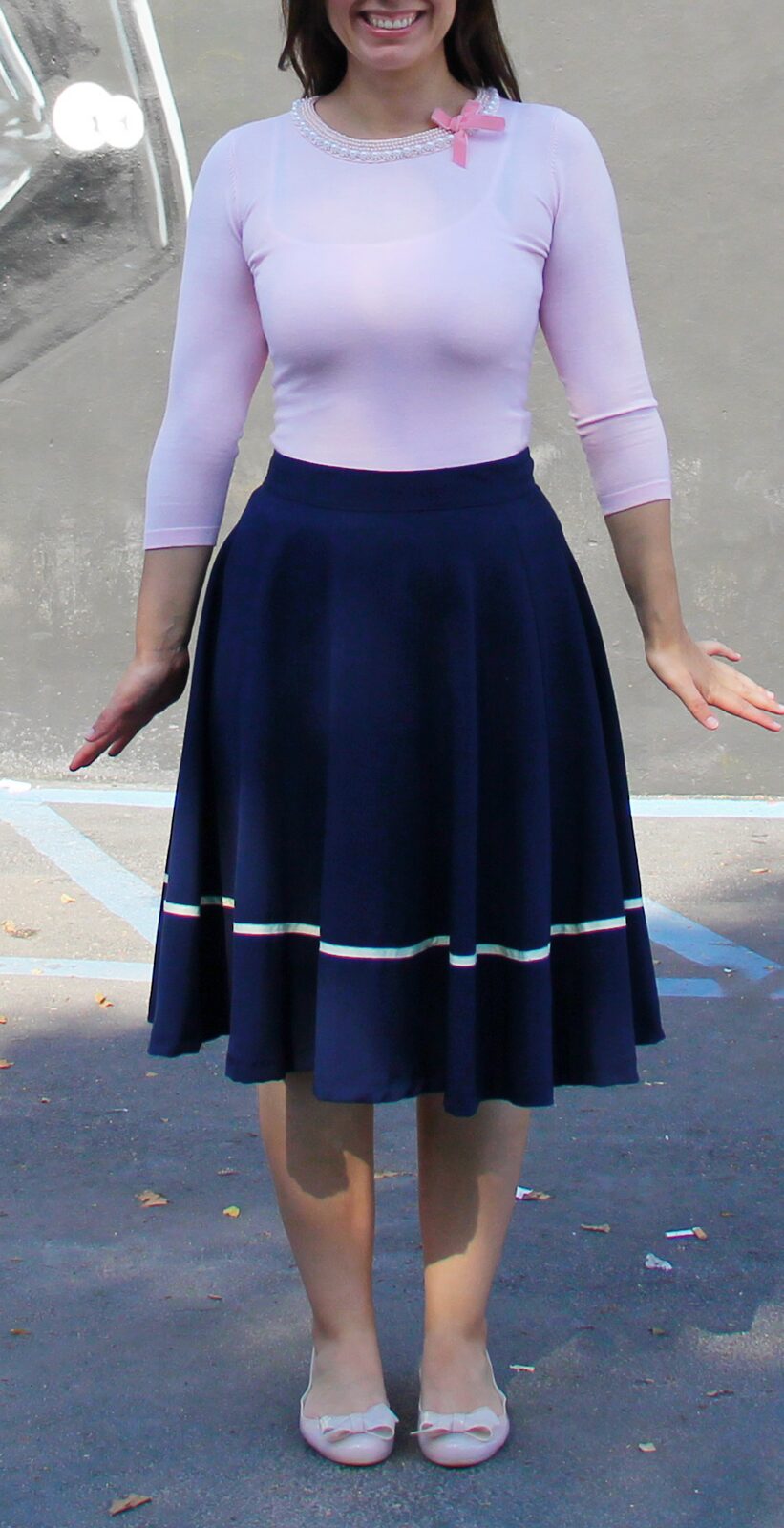 Pink sweater with neckline embellishment with navy midi skirt by Vader mural.