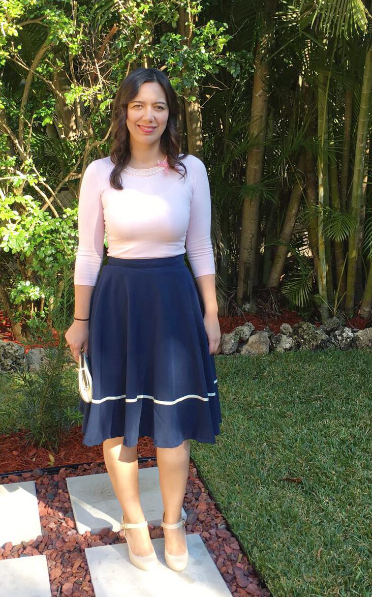 Pink sweater with neckline embellishment with navy midi skirt